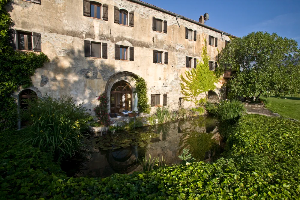 Restaurierte alte Olivenmühle in der Balagne, Korsika, mit Teich und umgebender Vegetation