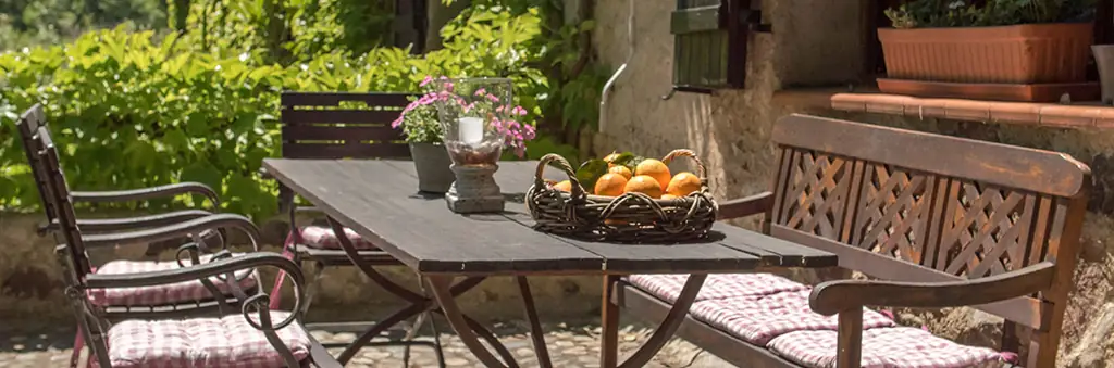 Gemütliche Terrassenwohnung mit rustikalem Gartentisch und Korb frischer Früchte