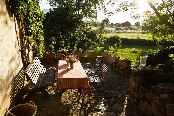 Gartenwohnung - Teil unserer Ferienwohnungen in Korsika mit Steinterrasse, Esstisch und Blick ins Grüne