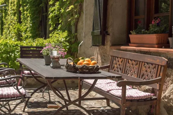 Gemütliche Terrassenwohnung mit rustikalem Gartentisch und Korb frischer Früchte